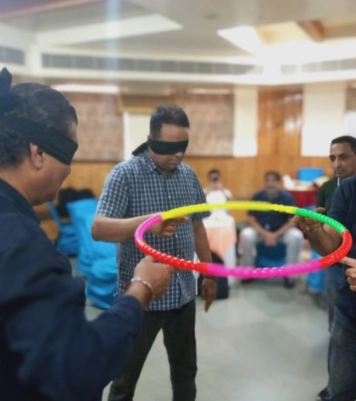 The staff members, full of joy, play and laugh together as they enjoy a game with a hula hoop.