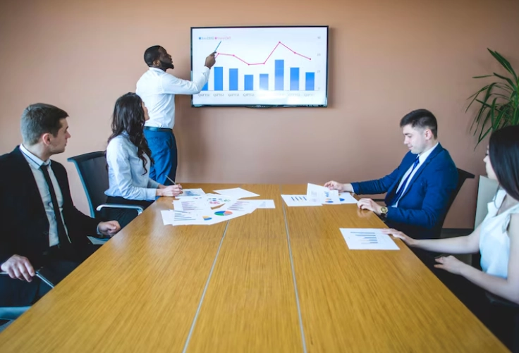 Corporate executives convened in a conference room, with a male mentor leading the discussion