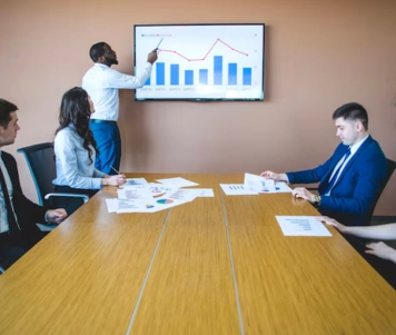 Corporate executives convened in a conference room, with a male mentor leading the discussion