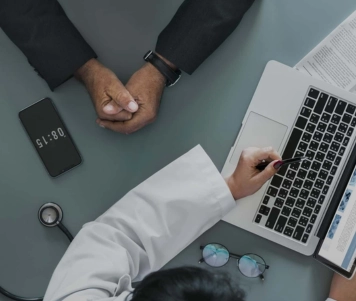 A physician is undergoing health care sales training while displaying some information on the laptop